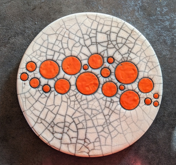 Sous-de-plat blanc et orange en céramique, décoratif et artisanal, créé à l’Atelier de la Terre Ronde.